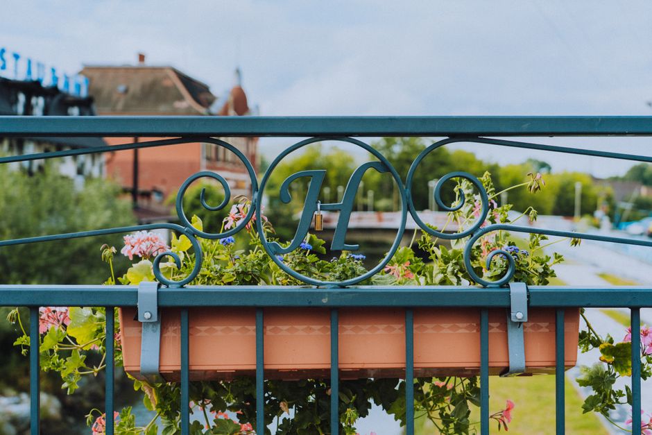 A close-up view of a rectangular terracotta flower box filled with a variety of vibrant, freshly cut flowers including pink geraniums, purple lobelias, and yellow petunias, arranged in a dense, lush d